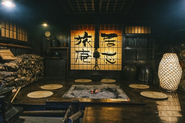 Traditionelle Feuerstelle eines Onsen in einem holzverkleideten Raum mit Kalligrafie